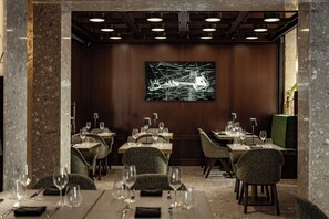 Un restaurante con mesas dispuestas para comer, una gran obra de arte en la pared y un diseño moderno en el techo.