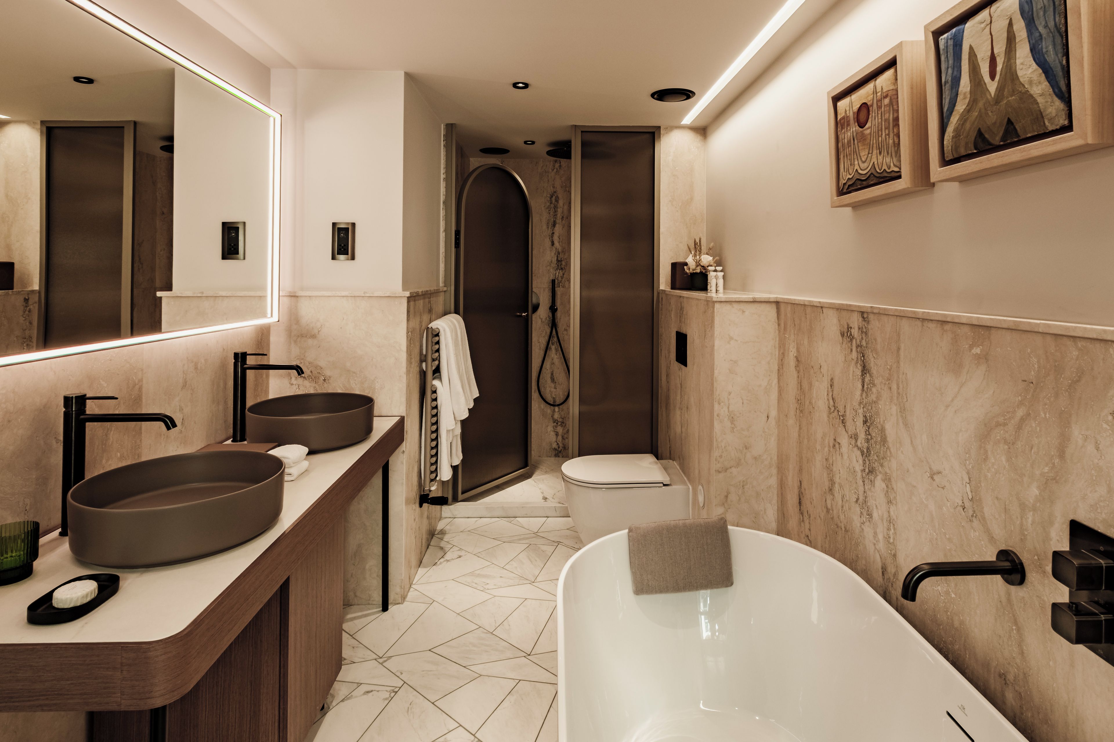 Un baño moderno con una bañera independiente, un espejo grande y un tocador doble.