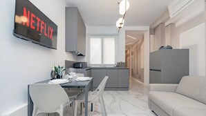Una cocina moderna con comedor, un televisor montado en la pared y un sofá en la sala.