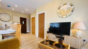 A living room with a television, a dining area with a table set, and a sofa.