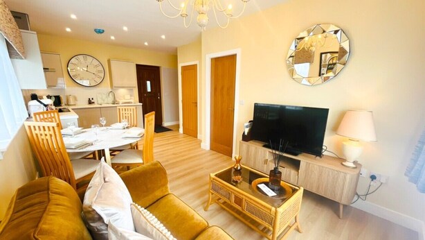 A living room with a sofa, television, and a dining area with a table set for two.