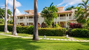 Un resort con un edificio blanco, palmeras y un césped cuidado.