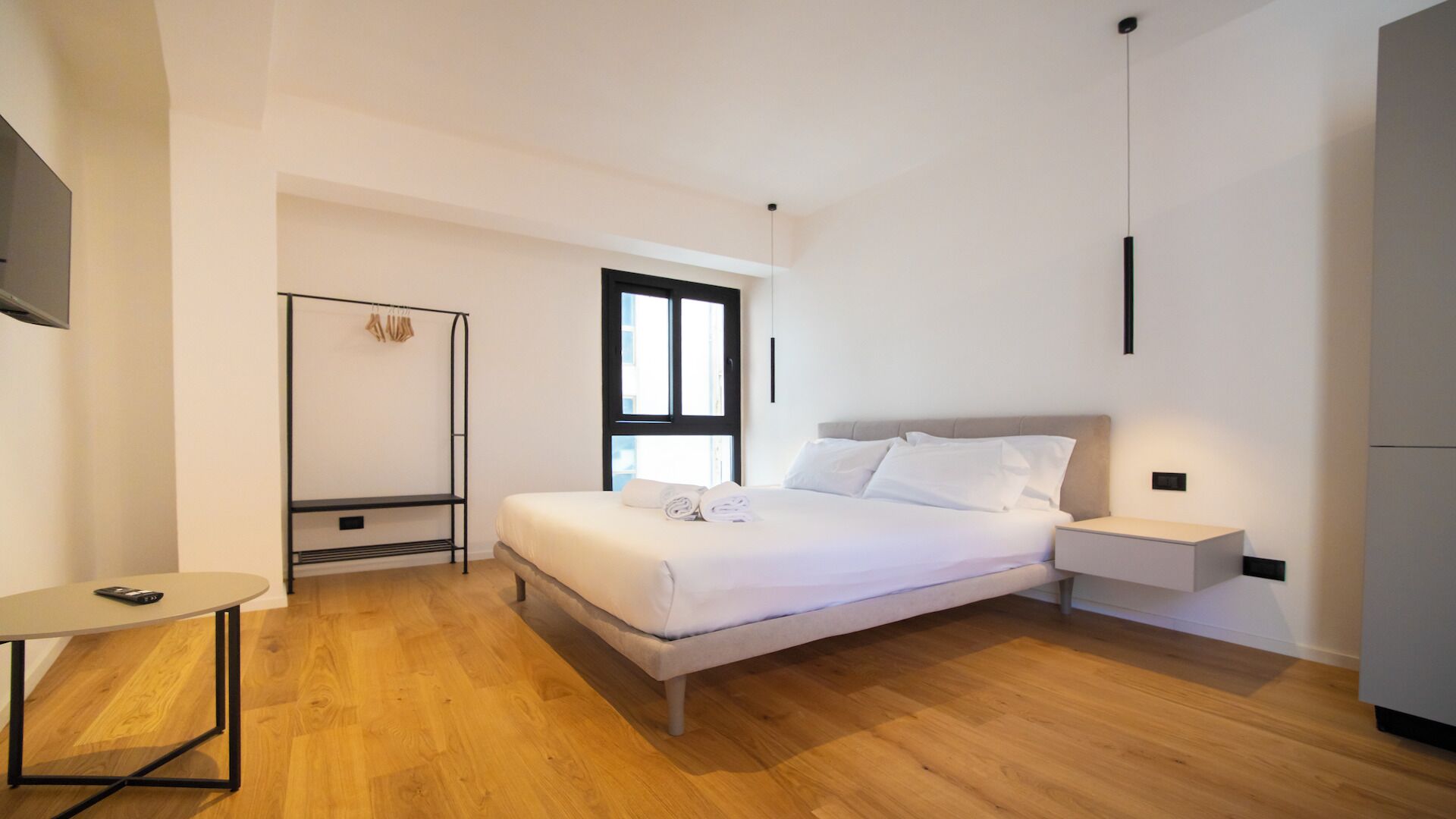 Une chambre moderne avec un lit, une table de chevet et une petite table sur laquelle se trouve un téléphone.