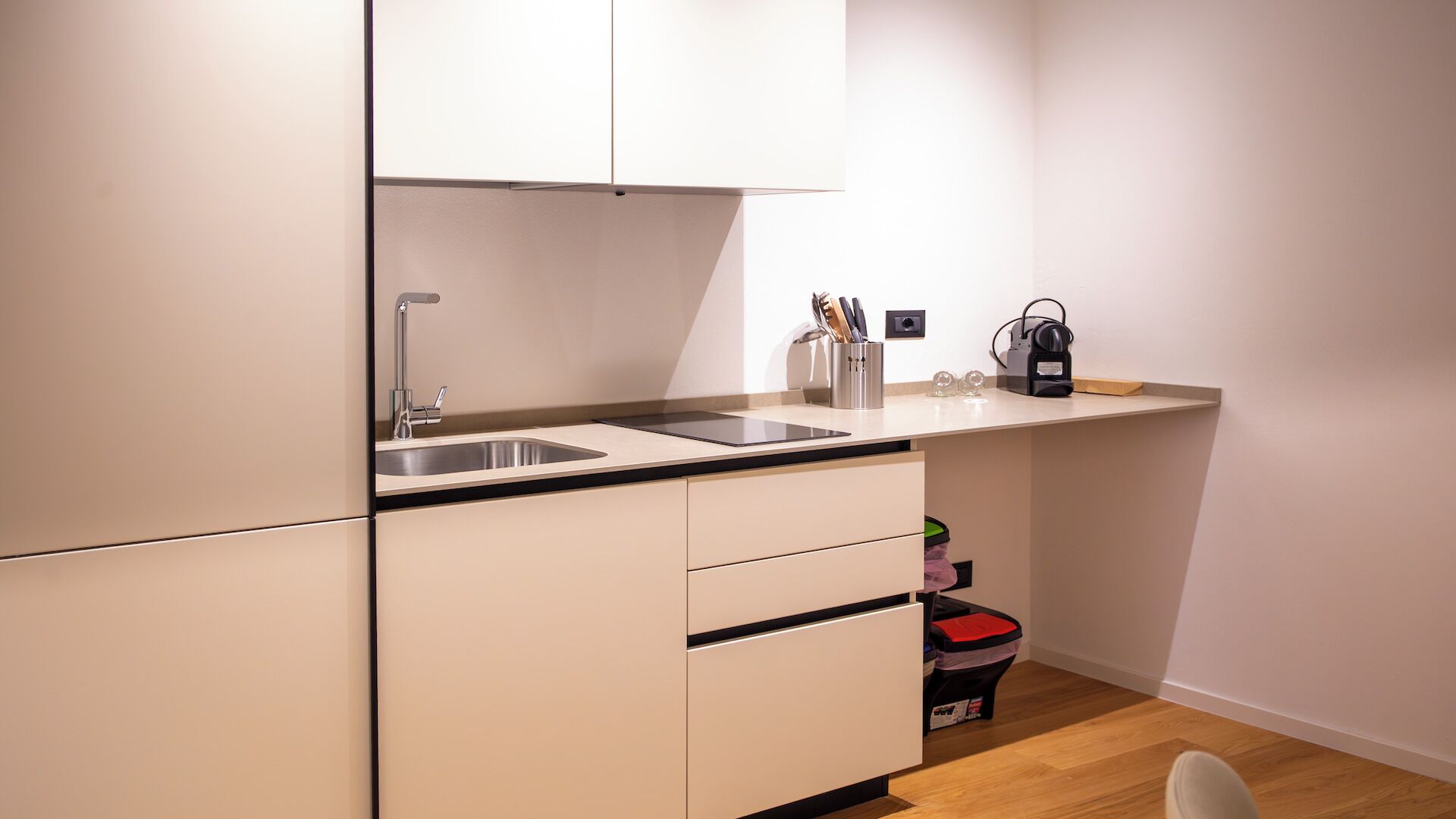 A compact kitchenette with a sink, countertop, and storage cabinets.