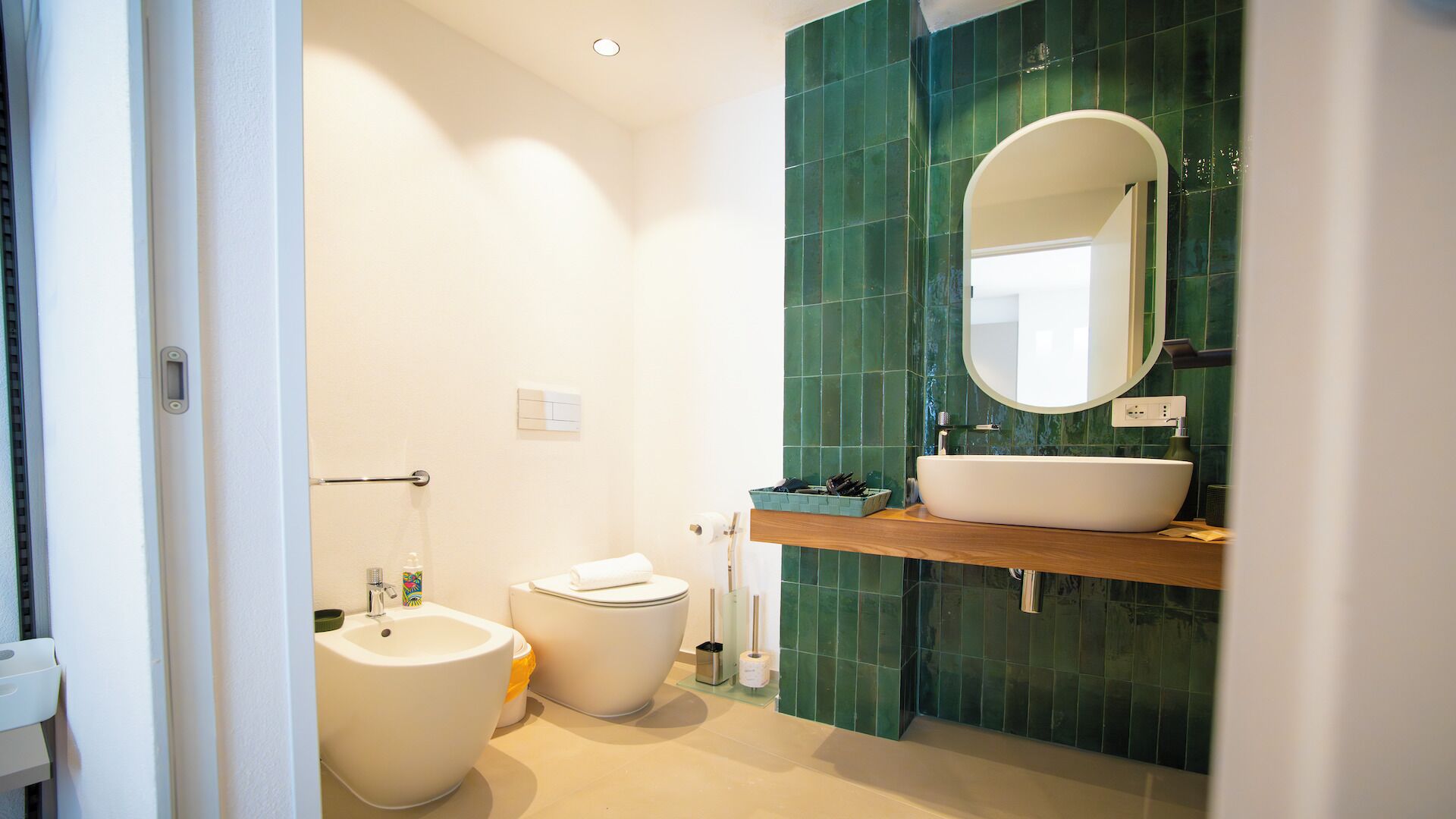A modern bathroom with a freestanding toilet, a pedestal sink, and a vanity with a large mirror.