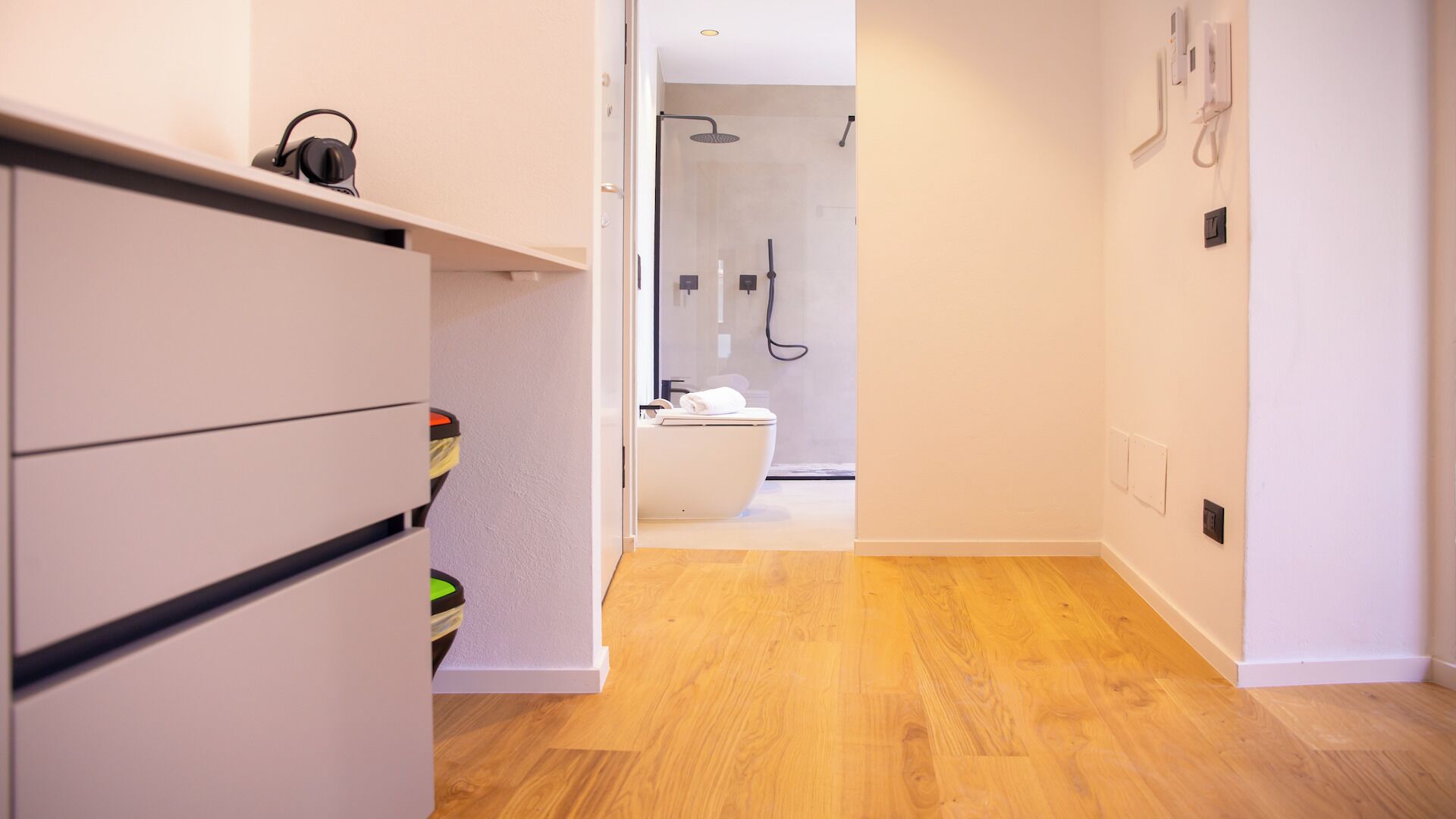 Un baño moderno con ducha, inodoro y puerta de vidrio que da acceso a la zona de la ducha.