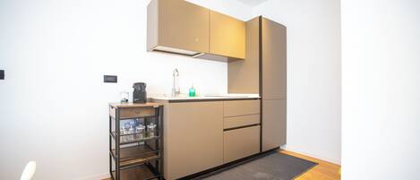 Een kleine keuken met een inbouwoven, een spoelbak en een klein aanrecht.