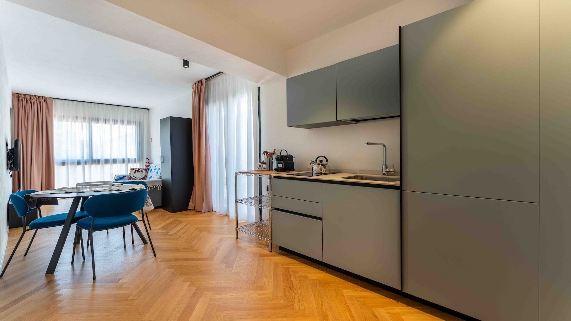 A compact kitchen with a dining area, a built-in oven, and a flat-screen TV.