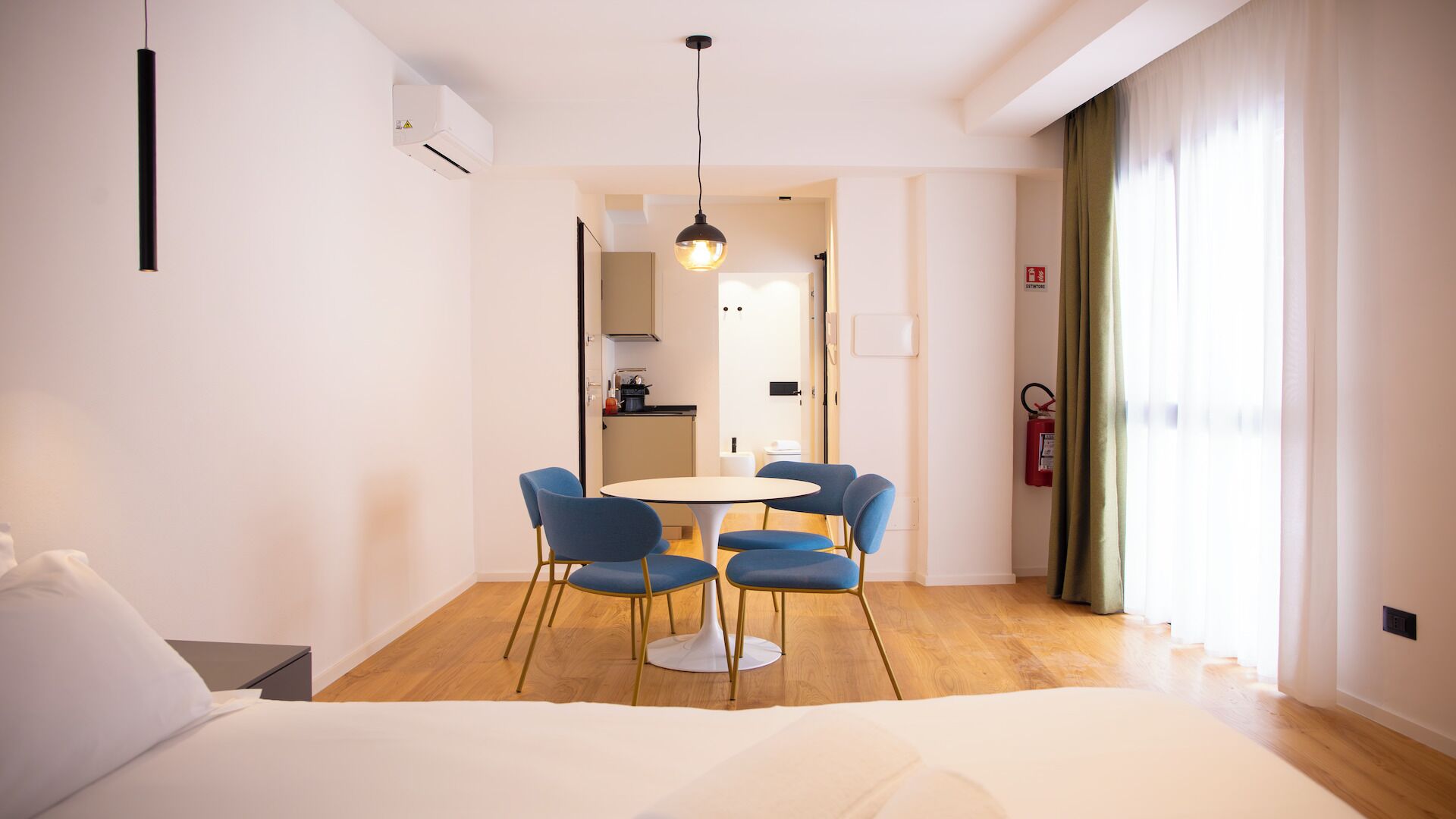 Een hotelkamer met een bed, een eettafel met stoelen, een kitchenette en uitzicht.