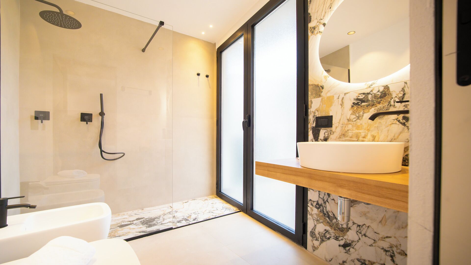 Un bagno moderno con una vasca, una doccia, uno specchio grande e uno schienale in marmo.