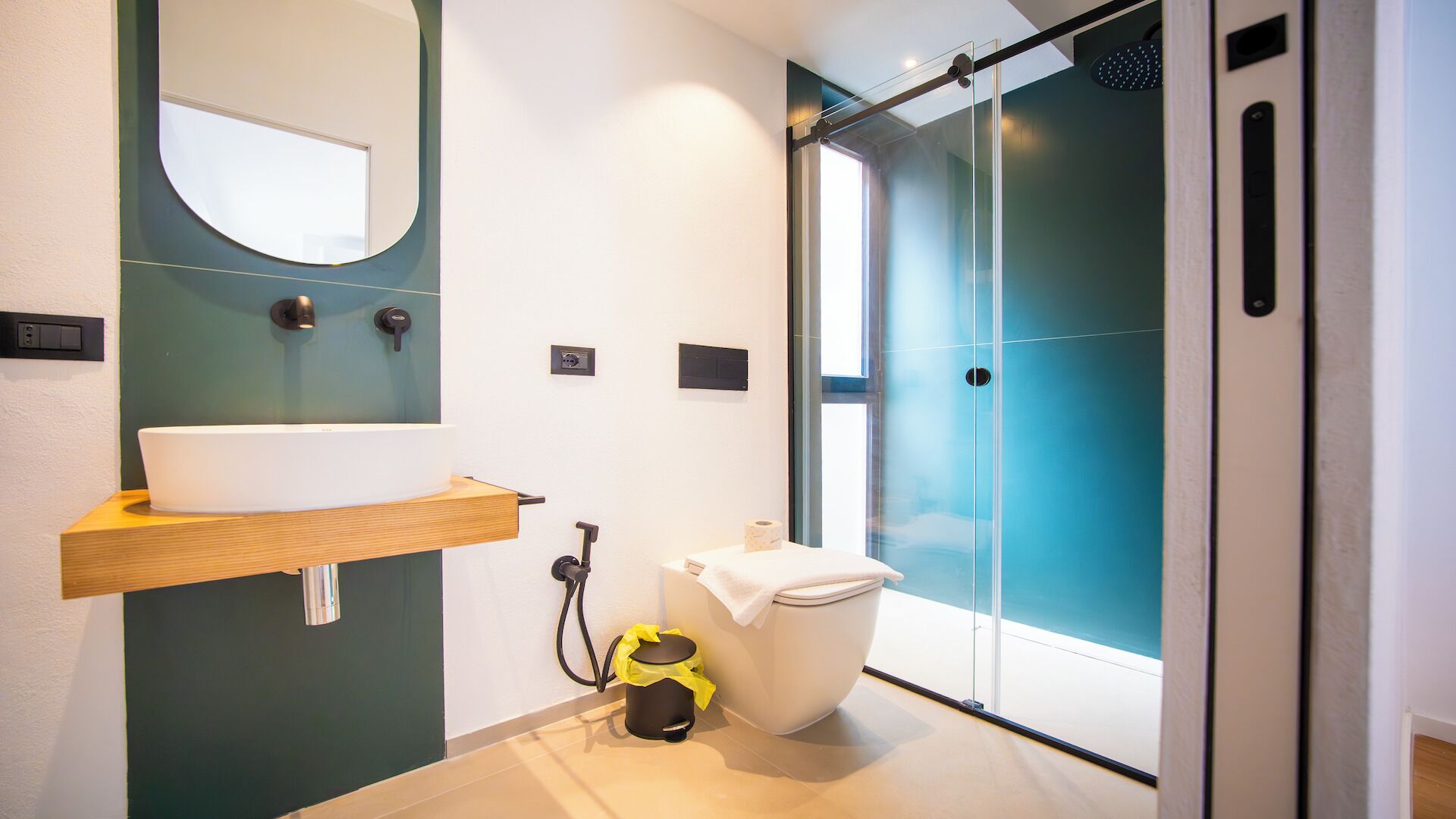 Une salle de bain moderne avec un lavabo blanc, un miroir, des toilettes et un espace douche.