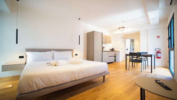 A modern hotel room with a large bed, a small table, a kitchenette, and a dining area. - Solemar Sicilia - Torre Maqueda (Palermo)