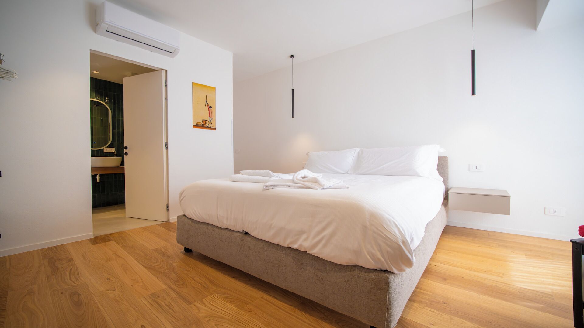 Un dormitorio con cama, mesita de noche, luz empotrada en la pared y aire acondicionado.