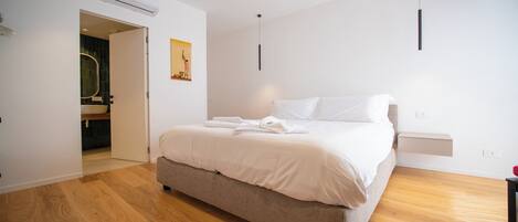 A bedroom with a bed, a bedside table, a wall-mounted light, and an air conditioning unit.