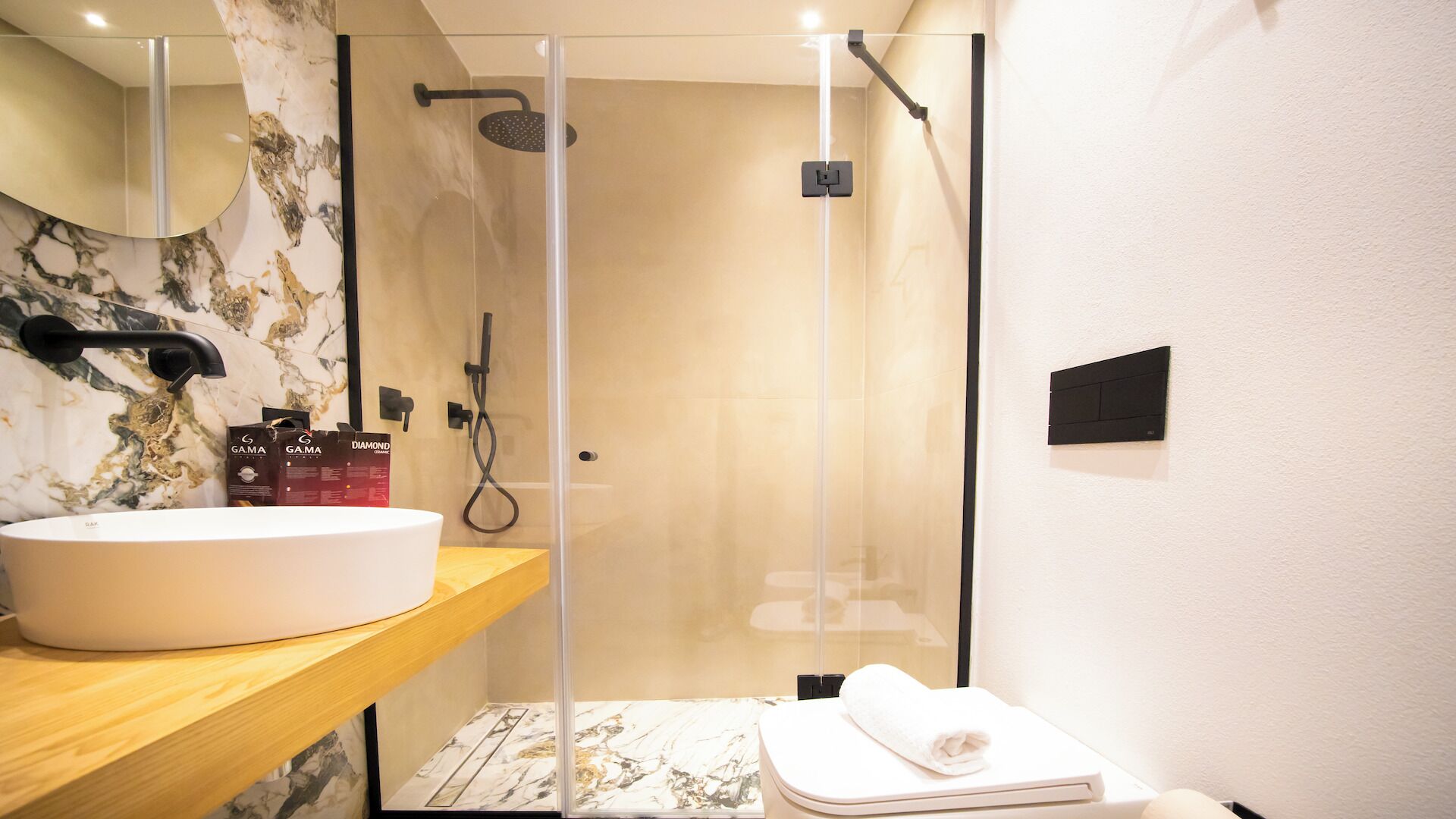 Une salle de bain avec un meuble-lavabo en marbre, un espace douche et une serviette sur le sol.