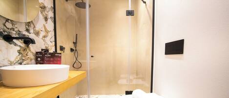 Une salle de bain avec un meuble-lavabo en marbre, un espace douche et une serviette sur le sol.