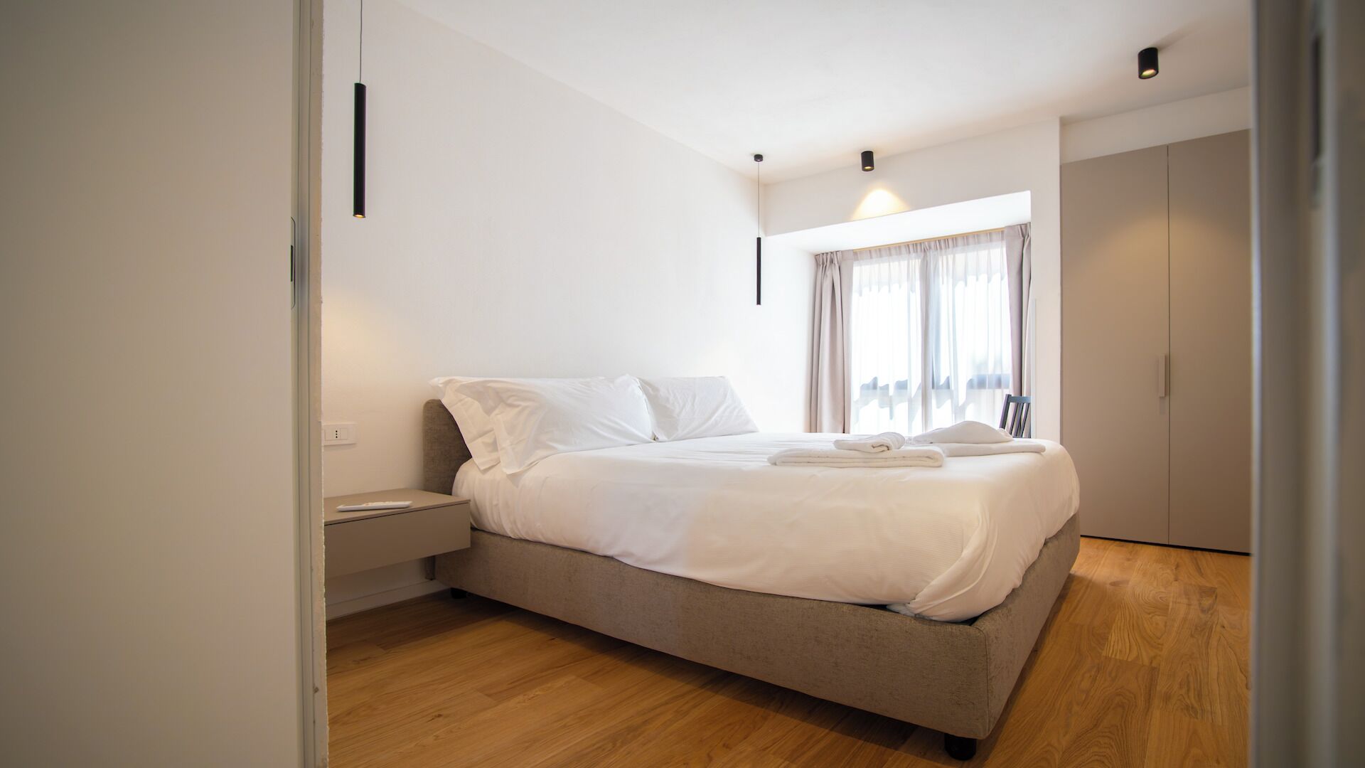 A bedroom with a bed, bedside table, and a wardrobe.