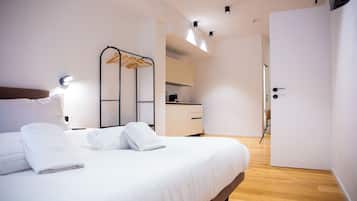 Una camera d'albergo moderna con un letto, un armadio, angolo cottura e bagno.