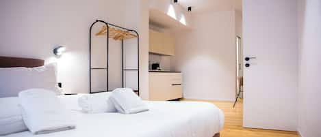 Una habitación de hotel moderna con cama, armario, kitchenette y baño.