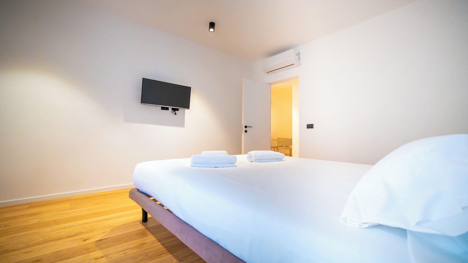 Een hotelkamer met een bed, een flatscreen televisie aan de muur en een airconditioning.