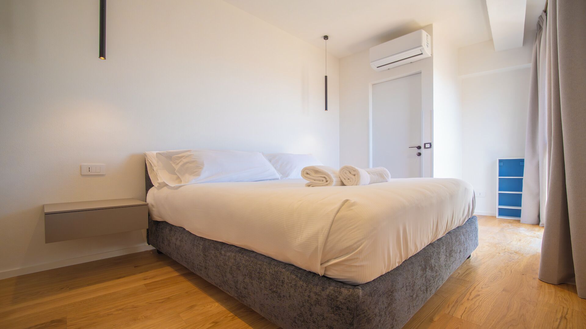 Een moderne slaapkamer met een bed, nachtkastje en een airconditioning.