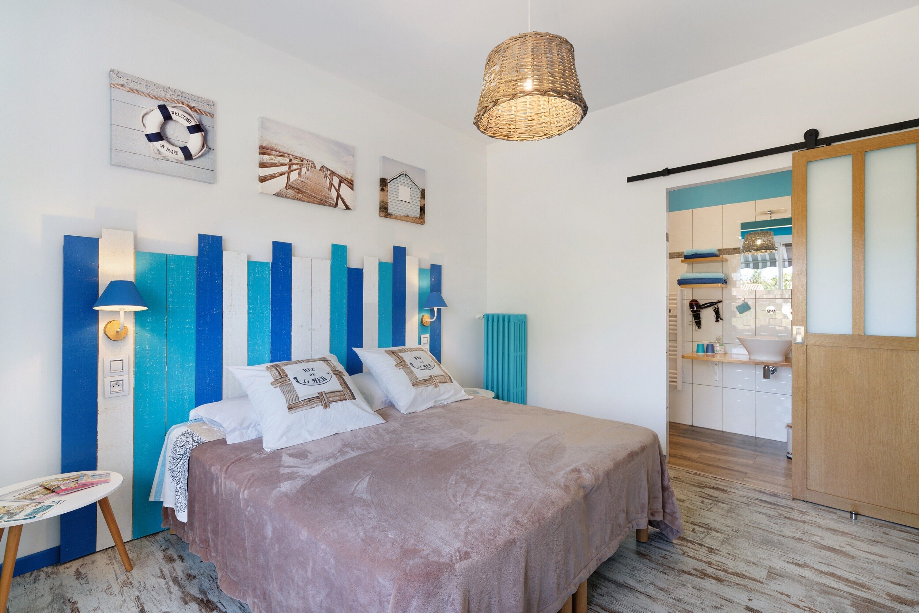 Une chambre à coucher avec un lit, des lampes de chevet, un luminaire suspendu et des œuvres d’art accrochées au mur.