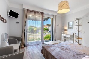 Une chambre d’hôtel équipée d’un lit, d’un bureau, d’une chaise, d’une télévision et offrant une vue sur l’extérieur.