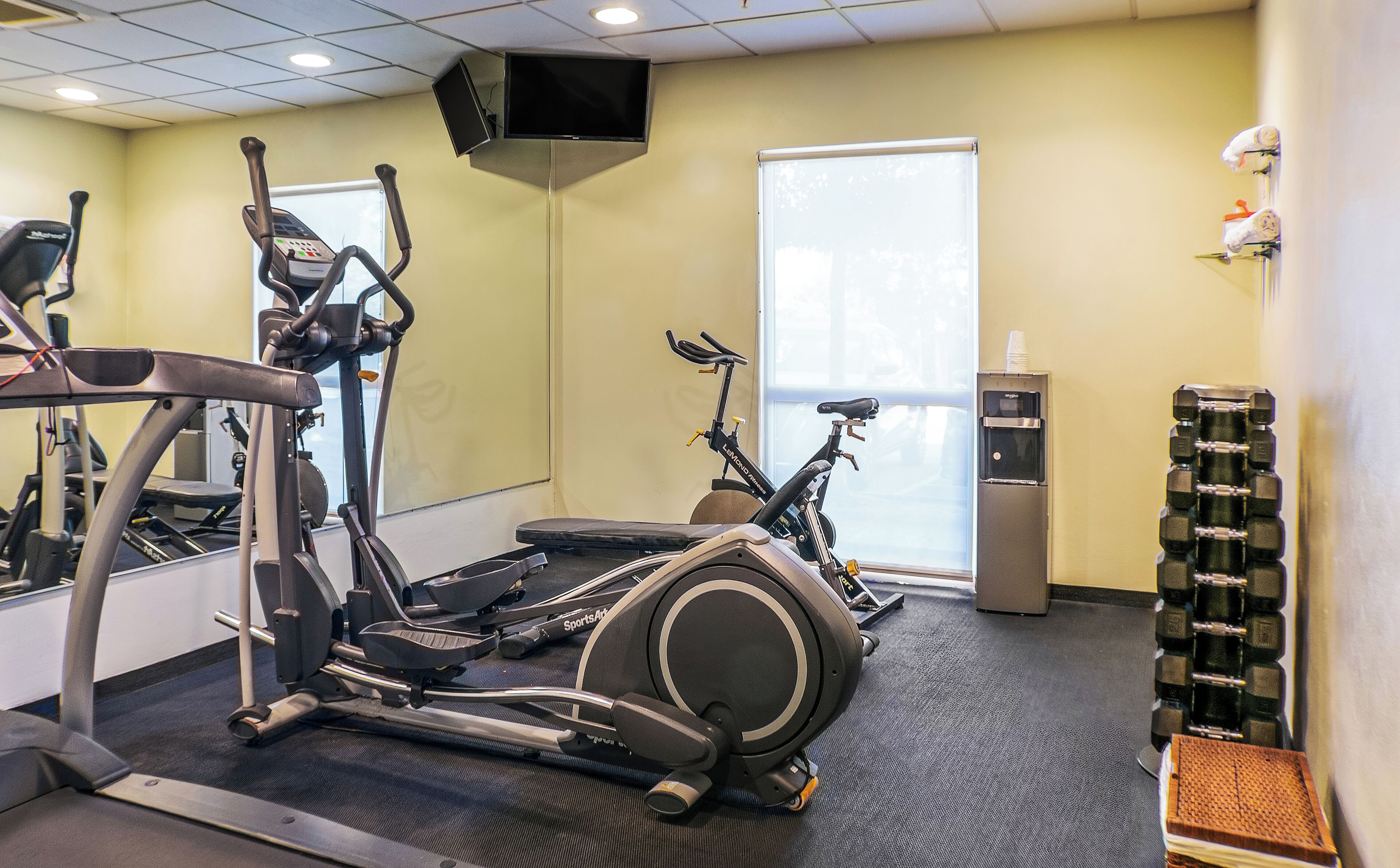 Una palestra con tapis roulant, cyclette e un distributore d'acqua.