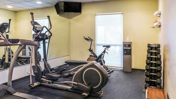 Una palestra con tapis roulant, cyclette e un distributore d'acqua.