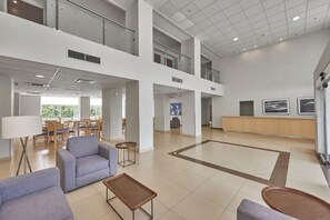 A spacious lobby with a high ceiling, a reception desk, and seating areas.