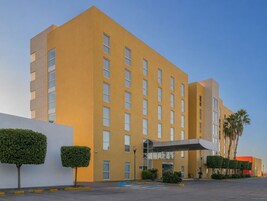 Un hotel de varios pisos con fachada plana, amplias ventanas y un acceso cubierto.