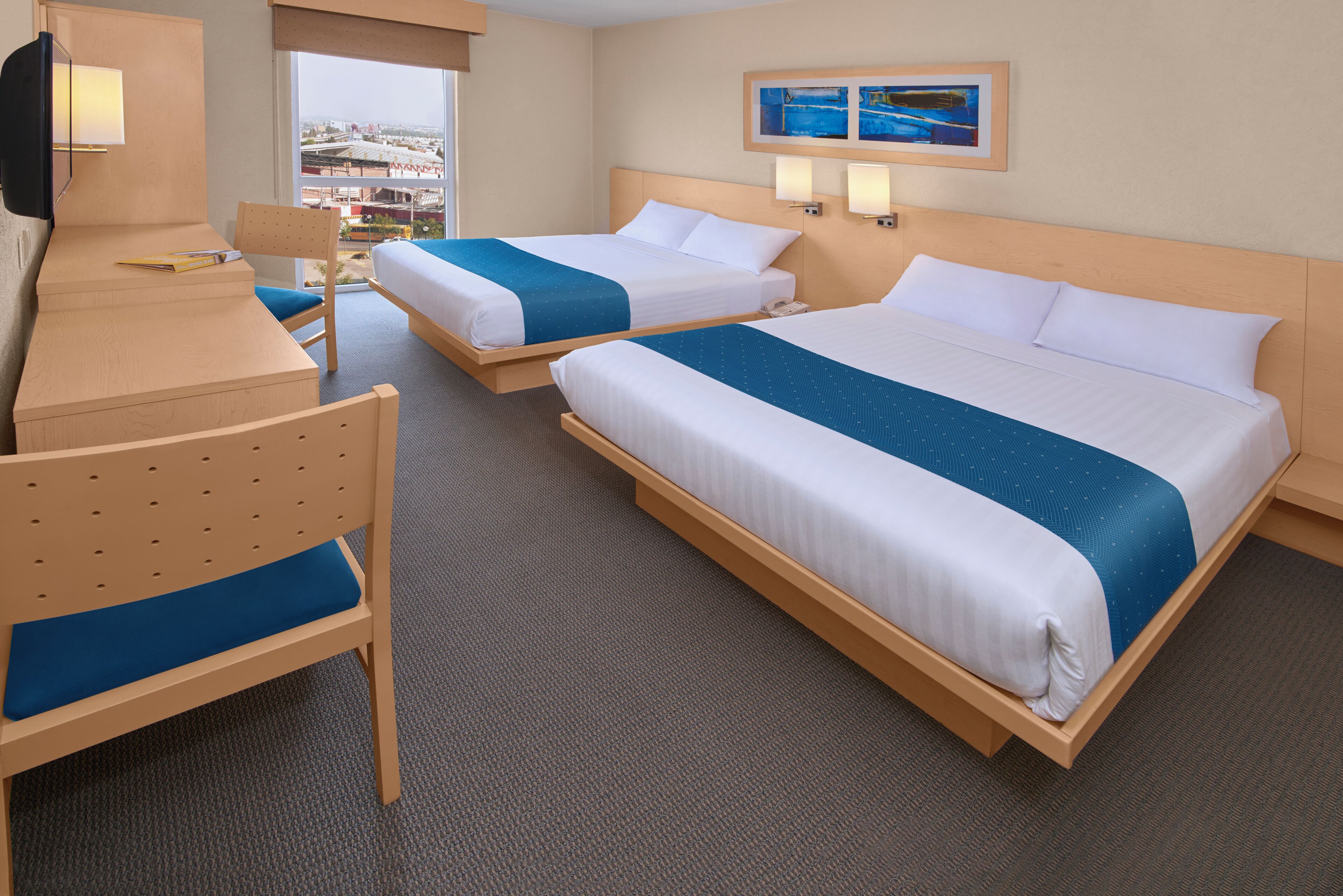 A hotel room with two beds, a desk, and a chair.