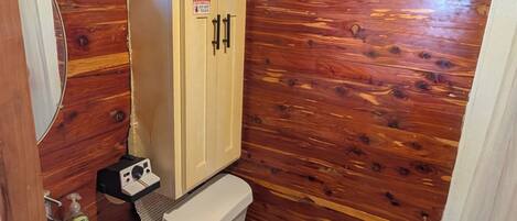 A wooden cabin bathroom with a wooden vanity, a sink, a toilet, and a window.