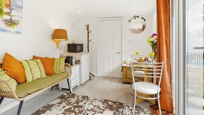 A compact living space with a sofa, dining table, and a kitchenette area.
