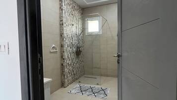 A bathroom with a shower, a toilet, and a sink.