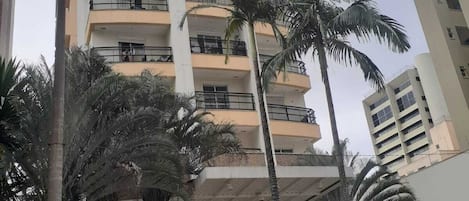A multi-story building with balconies, palm trees, and a glass entrance.