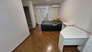 Ein kleines, gemütliches Zimmer mit Bett, Schreibtisch und einem Fenster mit Jalousien.