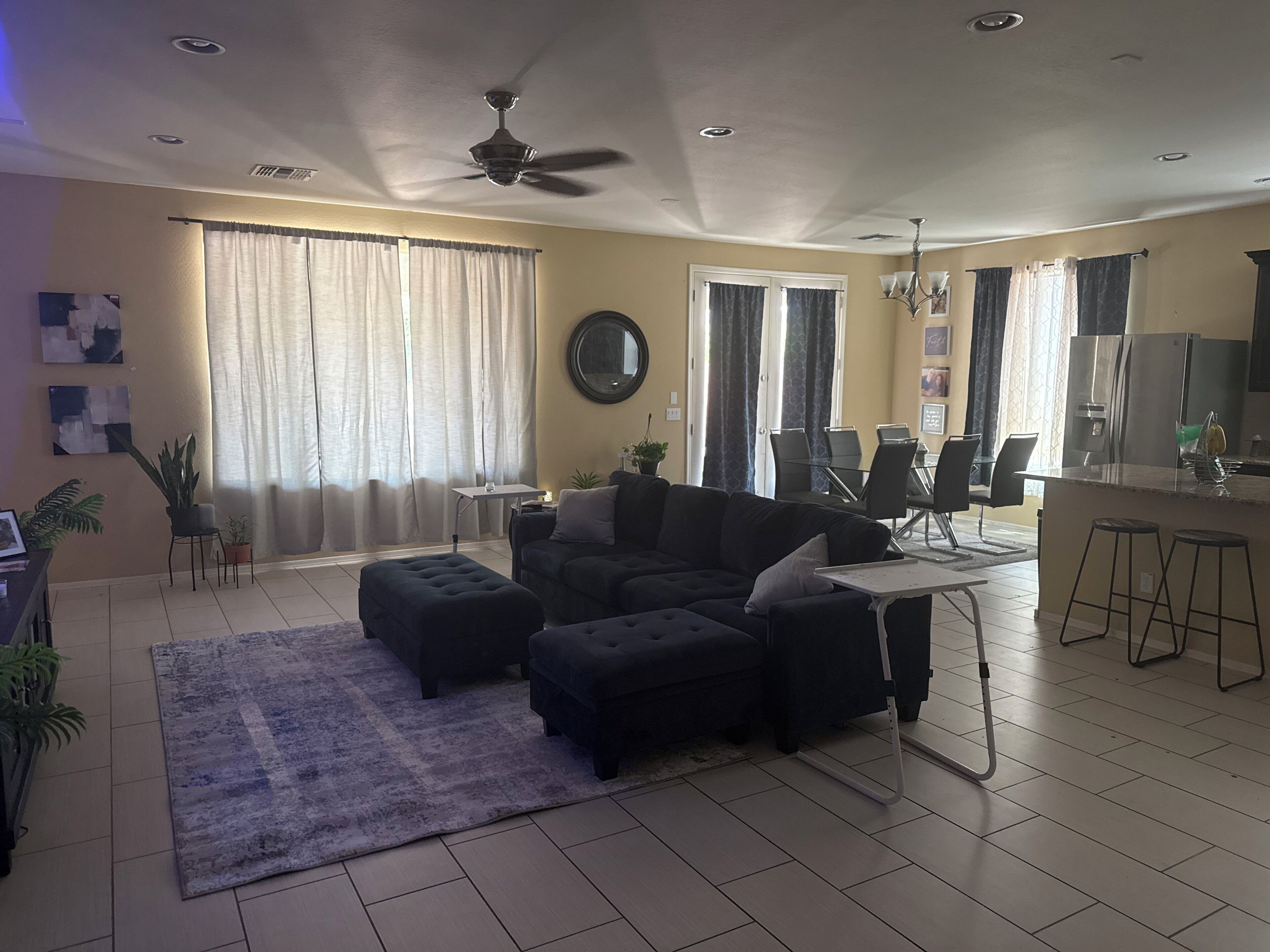 A living room with a sofa, ottoman, and a dining area with chairs and a table.