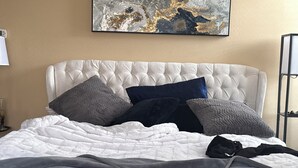 Ein Bett mit einem gesteppten Kopfteil, mehreren Kissen und einer Decke.