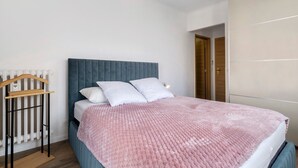 Una camera da letto con un letto, un termosifone, un appendiabiti in legno e un armadio.