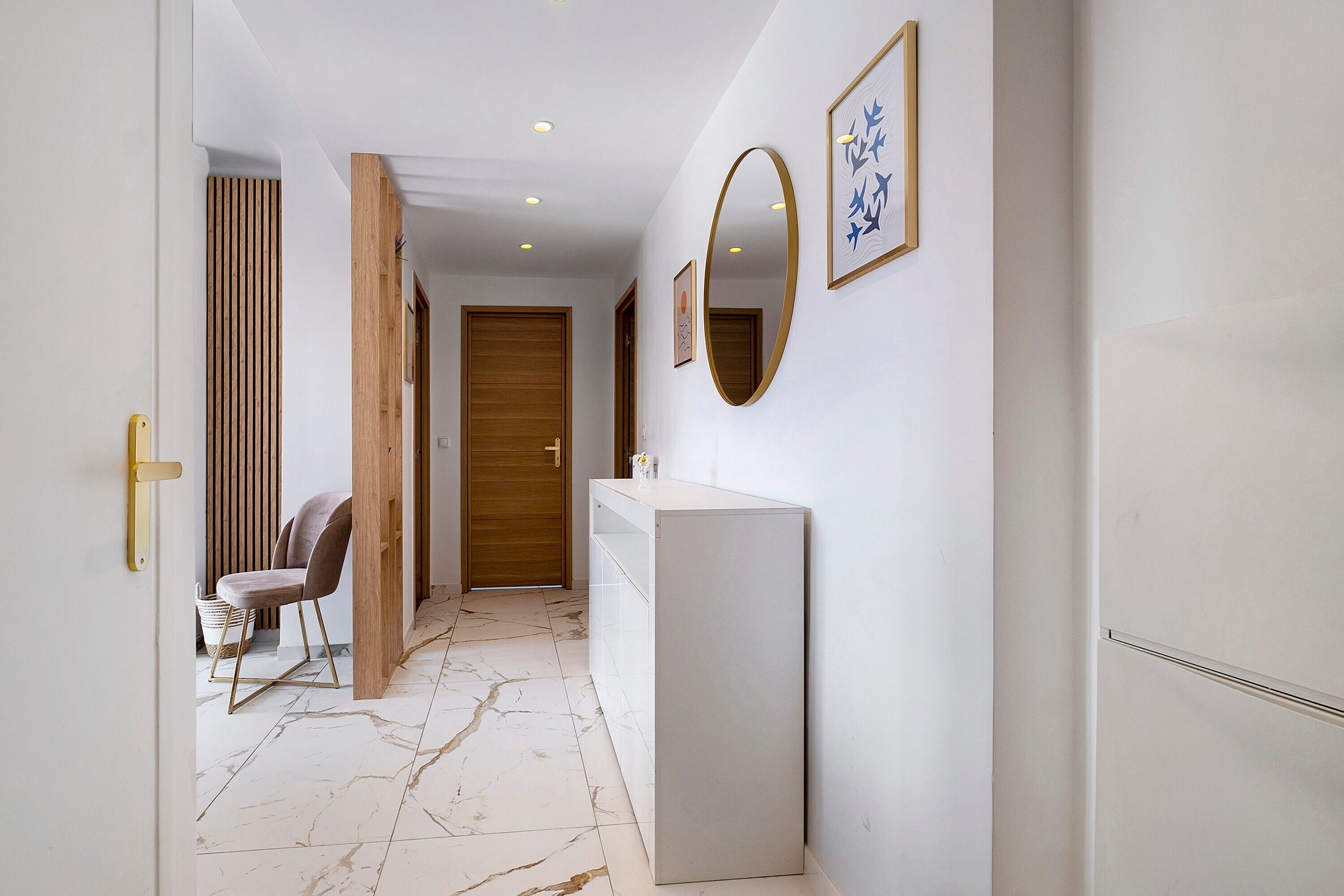 A hallway with a white wall, a wooden door, a white counter, and a chair.
