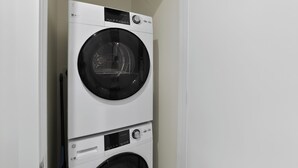 Una lavadora y secadora apiladas en una habitación con paredes blancas.
