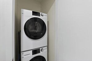 Eine übereinander gestellte Waschmaschine und ein Trockner in einem Raum mit weißen Wänden.