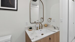 A bathroom with a white sink, gold fixtures, a marble countertop, and a framed artwork on the wall. - Modern Luxury Studio, Rooftop Pool, Wynwood (Miami)