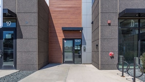 Entrada de un edificio moderno con puerta de vidrio, panel de pared de madera y un letrero con el número 1247.