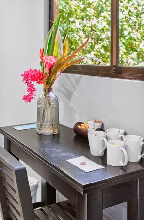 Une table avec un vase de fleurs, un portefeuille et plusieurs tasses blanches.