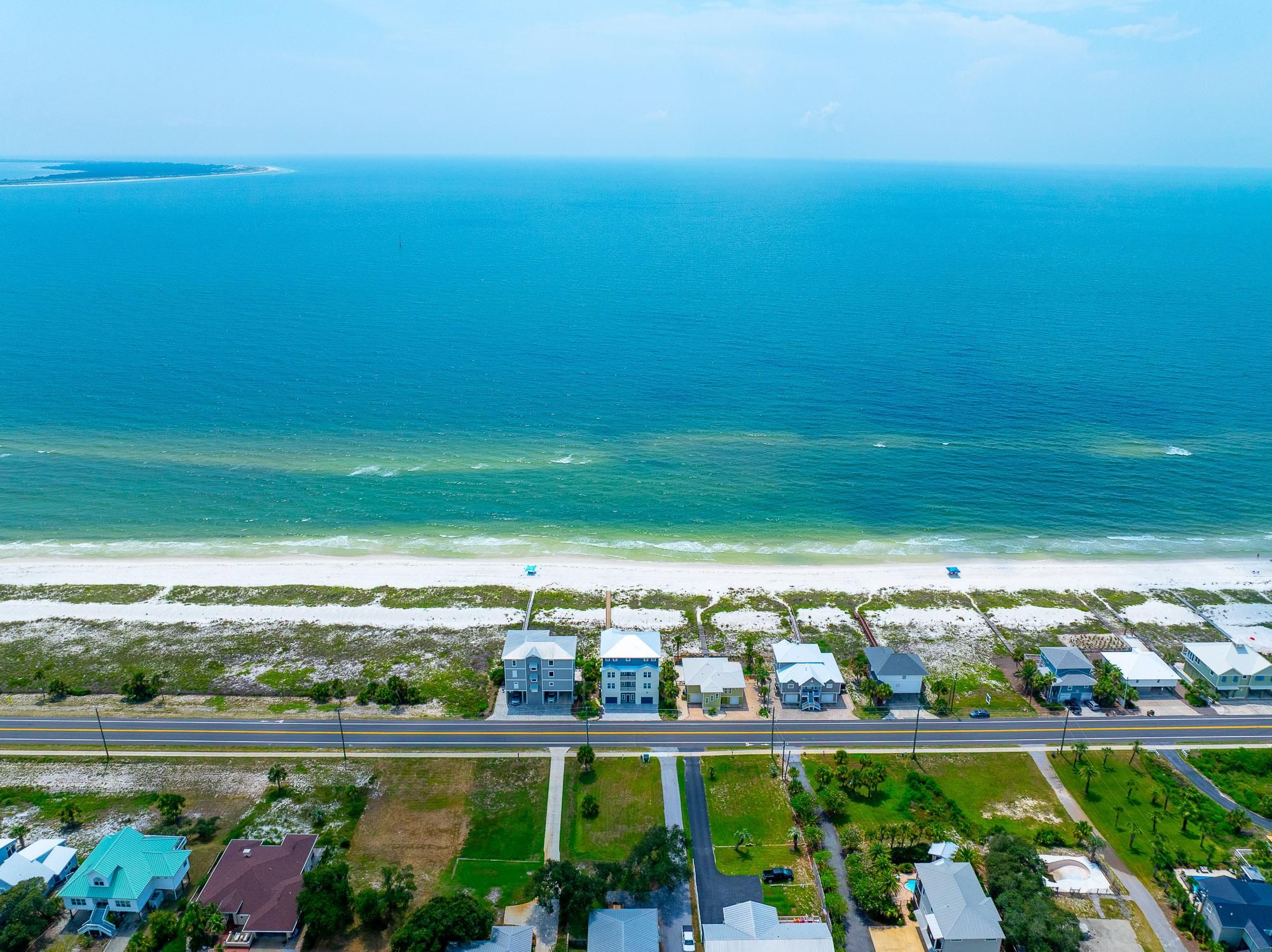 A coastal residential area with houses, a road, and a beach.