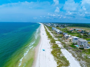 An aerial view of a coastal area with a beach, buildings, and a road. - Windward Crest (Port St. Joe)