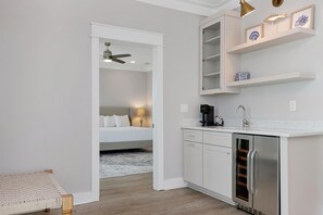 A modern hotel room with a bed, a desk, a coffee machine, and a mini-fridge. - Windward Crest (Port St. Joe)