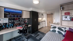 A modern, compact room with a desk, chair, bed, and kitchenette. - Student Only The View (Newcastle)